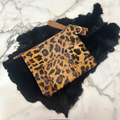 Leopard stenciled genuine cowhide clutch with gold hardware on black fur background