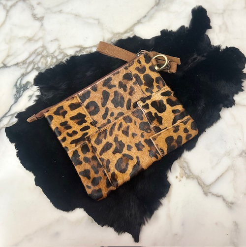 Leopard stenciled genuine cowhide clutch with gold hardware on black fur background